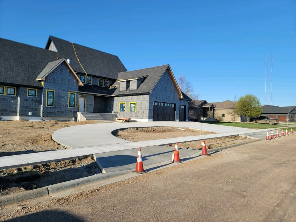 A curved driveway and new city sidewalk curing at a home under construction