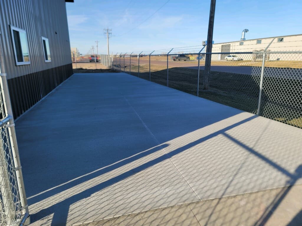 A broom-finished pad and apron at a fenced commercial building