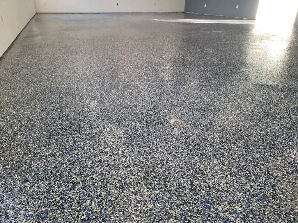 A color-chip epoxy floor across a finished interior