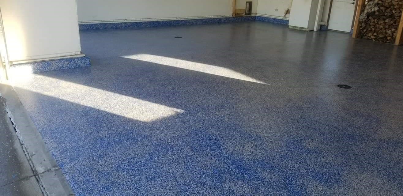 A blue color-chip epoxy garage floor with a matching cove base
