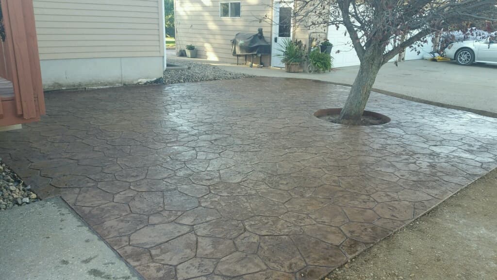 A stamped flagstone-pattern concrete patio wrapping a tree